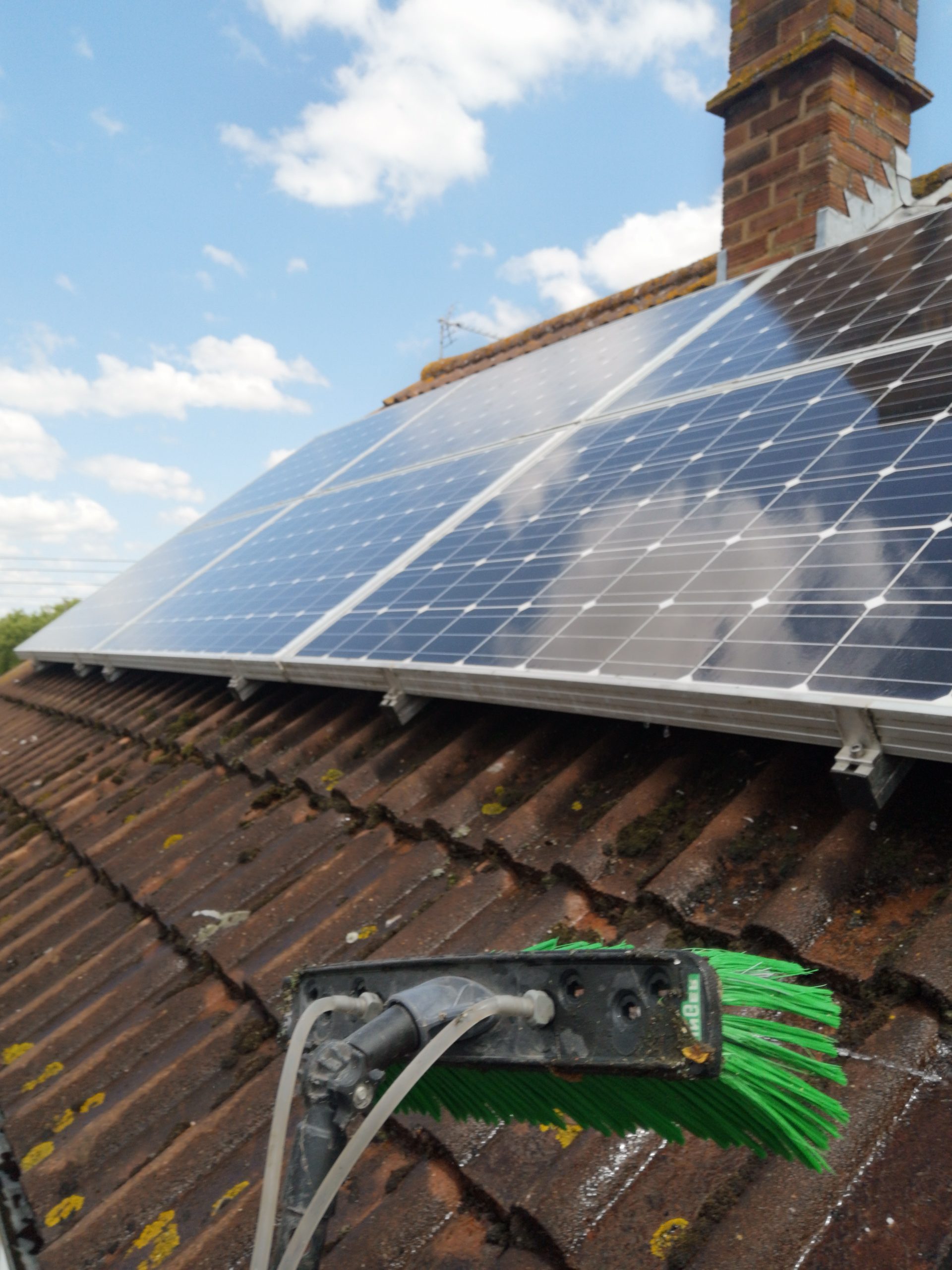 Technician cleaning solar panels on a residential roof in Gloucestershire for improved energy efficiency